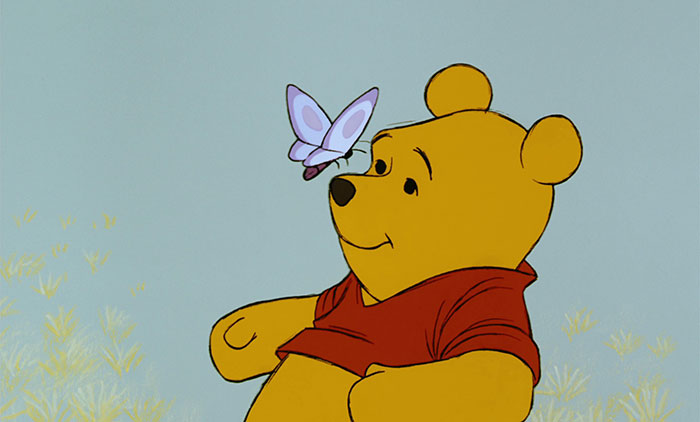 Cute animated character bear with a butterfly on its nose, creating an adorable moment in a soft background setting.