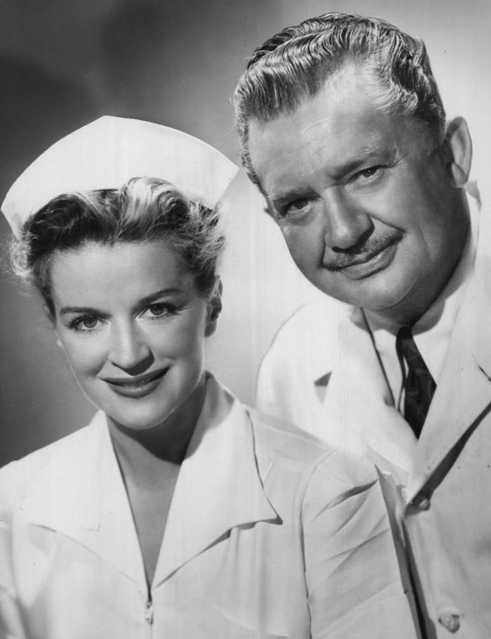 Black and white photo of a smiling nurse and doctor from a vintage medical TV show.