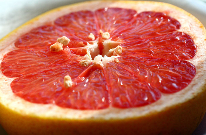 Close-up of a grapefruit slice highlighting texture and seeds, related to inedible foods and unusual edible items.