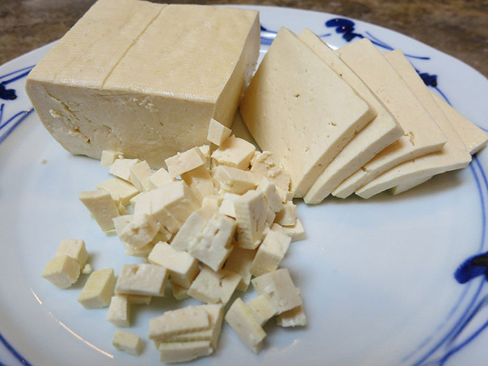 Blocks and diced pieces of tofu on a white plate, illustrating one of the most inedible foods according to adventurous eaters.