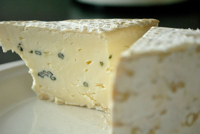 Close-up of a wedge of moldy cheese, one of the most inedible foods according to adventurous eaters.