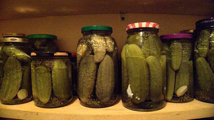 Jars of pickles on a wooden shelf, representing some of the most inedible foods according to adventurous eaters.