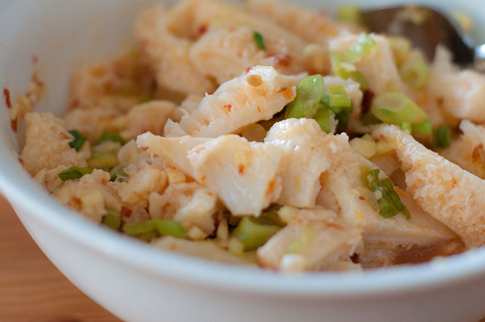 Close-up of a bowl containing edible tripe mixed with spices and chopped green onions, a unique inedible food item.