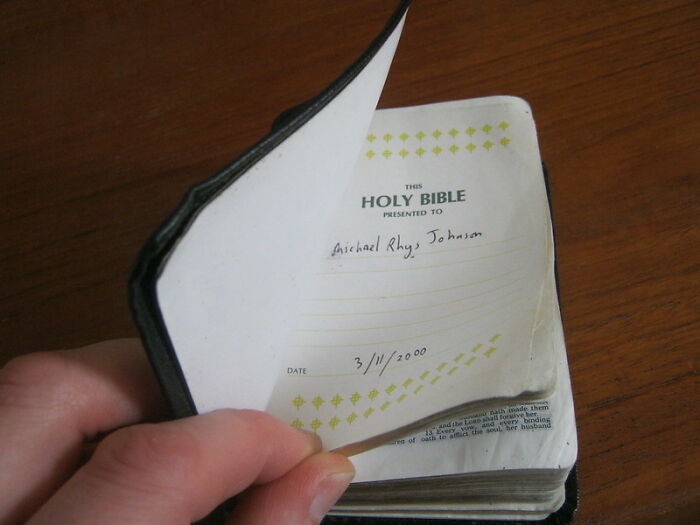 Hand flipping through the pages of a small Holy Bible, illustrating books that changed lives and blew minds.