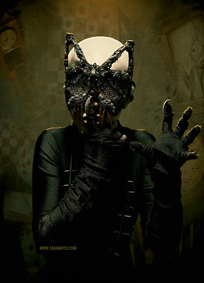 Dark Alice character wearing an elaborate mask with dark clothing in a surreal, Wonderland-inspired setting.