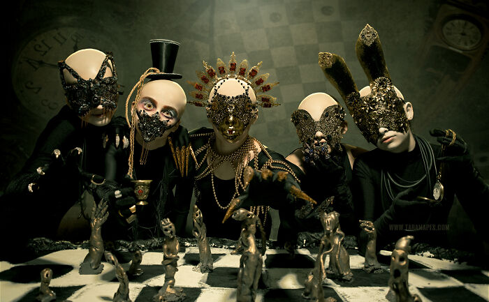 Dark Alice themed figures in elaborate masks, gathered around a chessboard, evoking a mysterious Wonderland atmosphere.