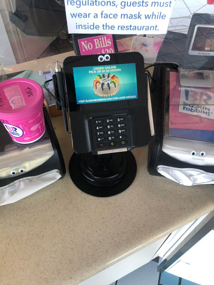 Payment terminal and receipt holders with wiggle eyes added, enhancing everyday objects in an eyebombing style.