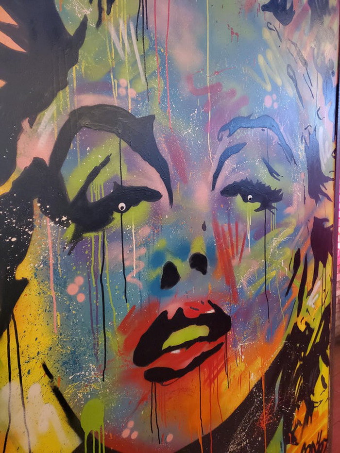 Colorful abstract face painting with wiggle eyes enhancing the random objects in the Eyebombing community style.