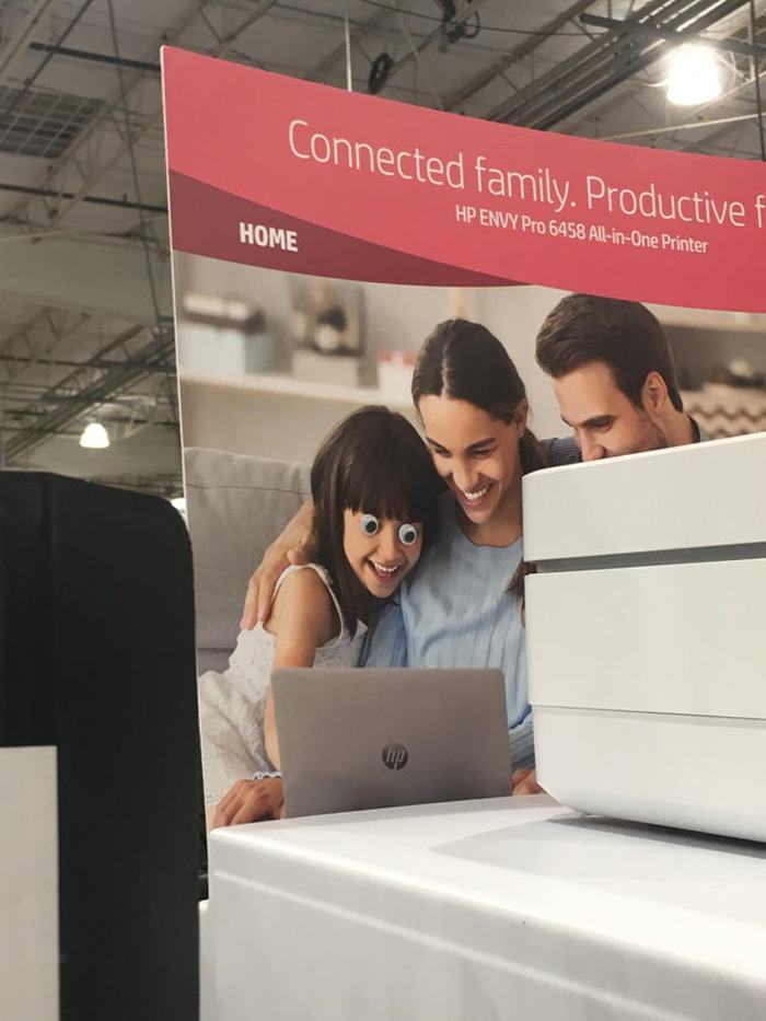 Family photo with wiggle eyes added to child’s face, enhancing the joyful moment in an eyebombing style.