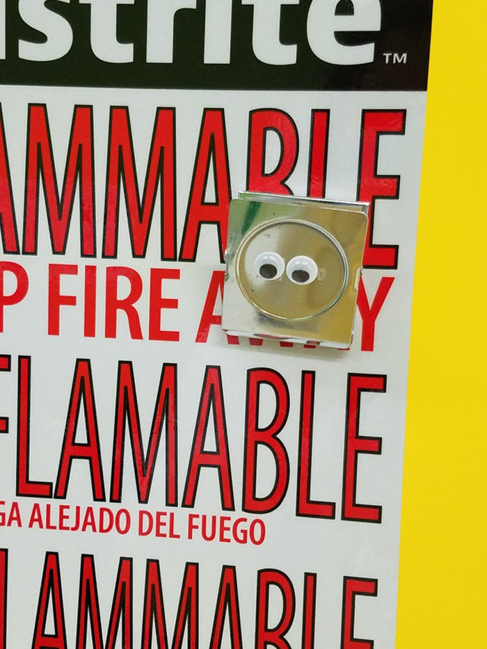 Flammable sign with a metal switch enhanced by wiggle eyes making the random object amusing in eyebombing style.