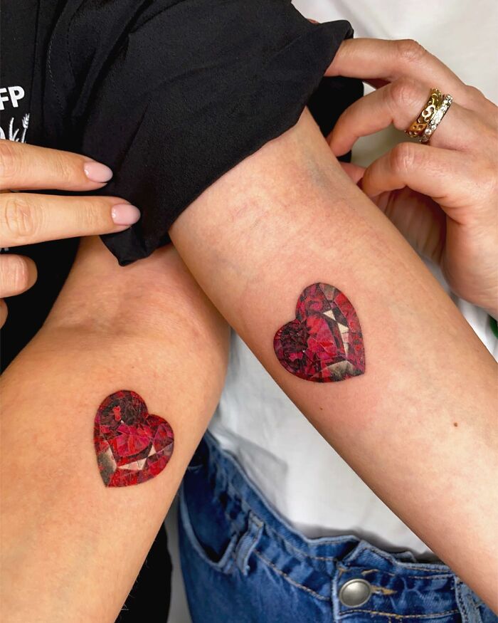 Heart-shaped tattoos resembling jewelry on two arms, showcasing intricate permanent jewelry designs.