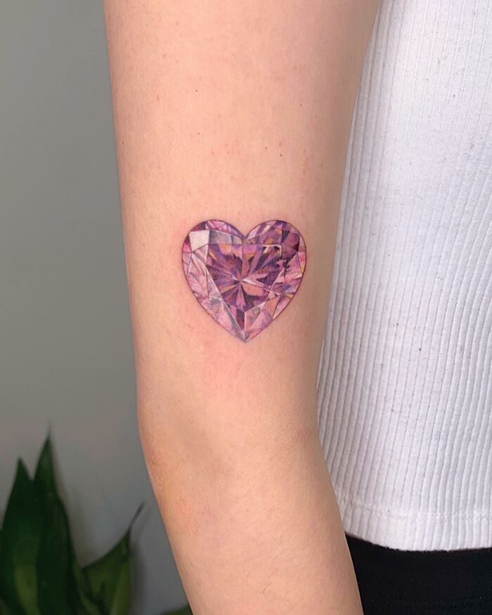 Heart-shaped diamond tattoo on arm, showcasing permanent jewelry style.