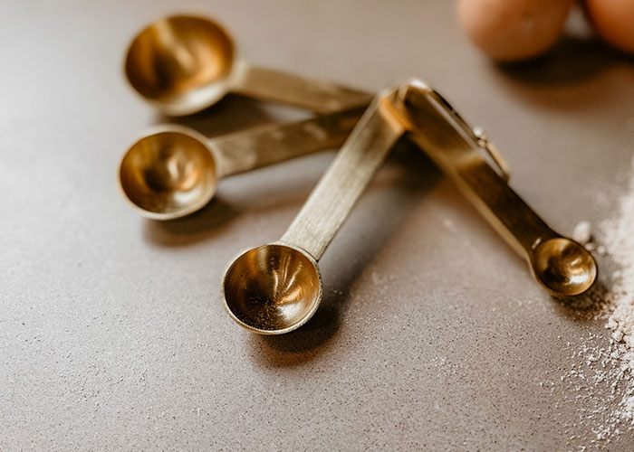 Set of brass measuring spoons on a kitchen counter, illustrating secret kitchen tools used by people in their kitchen routines.