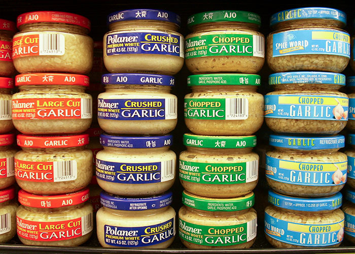 Jars of large cut, crushed, and chopped garlic arranged on a kitchen shelf showing common secret kitchen ingredients.
