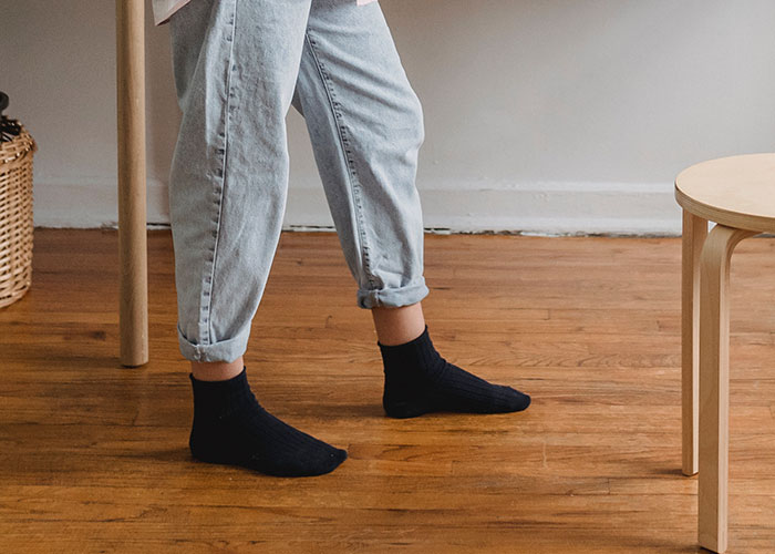 Person standing barefoot in socks and rolled-up jeans on wooden floor, revealing kitchen secrets concept.