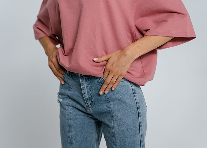 Person in casual outfit standing with hands on hips, illustrating things people do in their kitchen secrets.