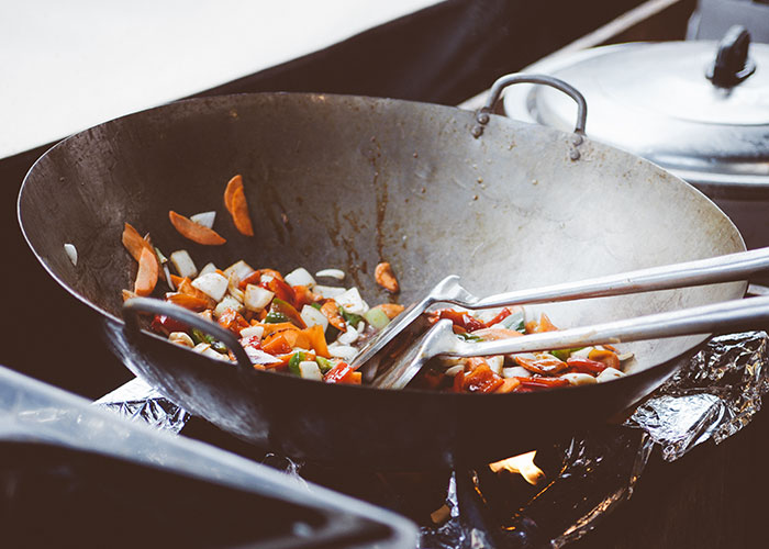 Wok cooking colorful vegetables over an open flame, showcasing secret kitchen things people do with their meals.