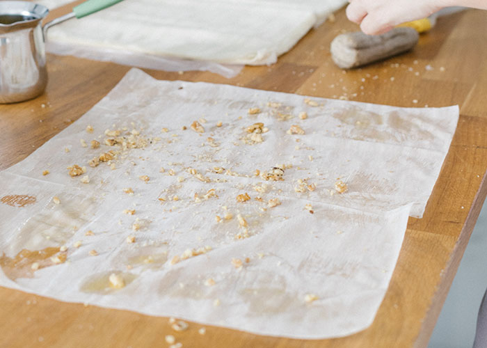 Crumbs and small food pieces scattered on kitchen countertop with hand preparing something on the side.