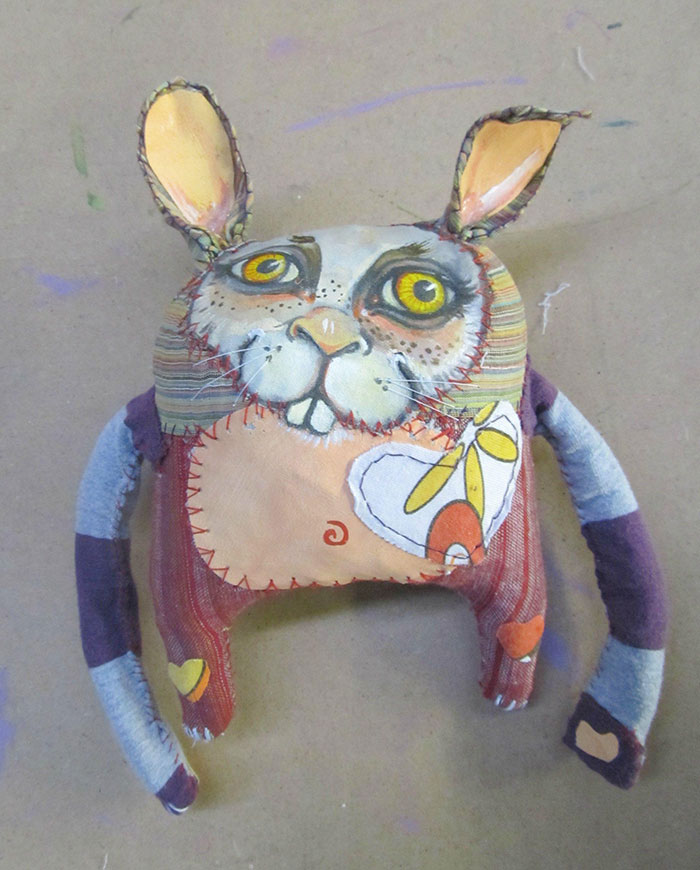 Creepy handmade stuffed toy with large yellow eyes and patchwork design, fitting the creepy toys nightmare theme.