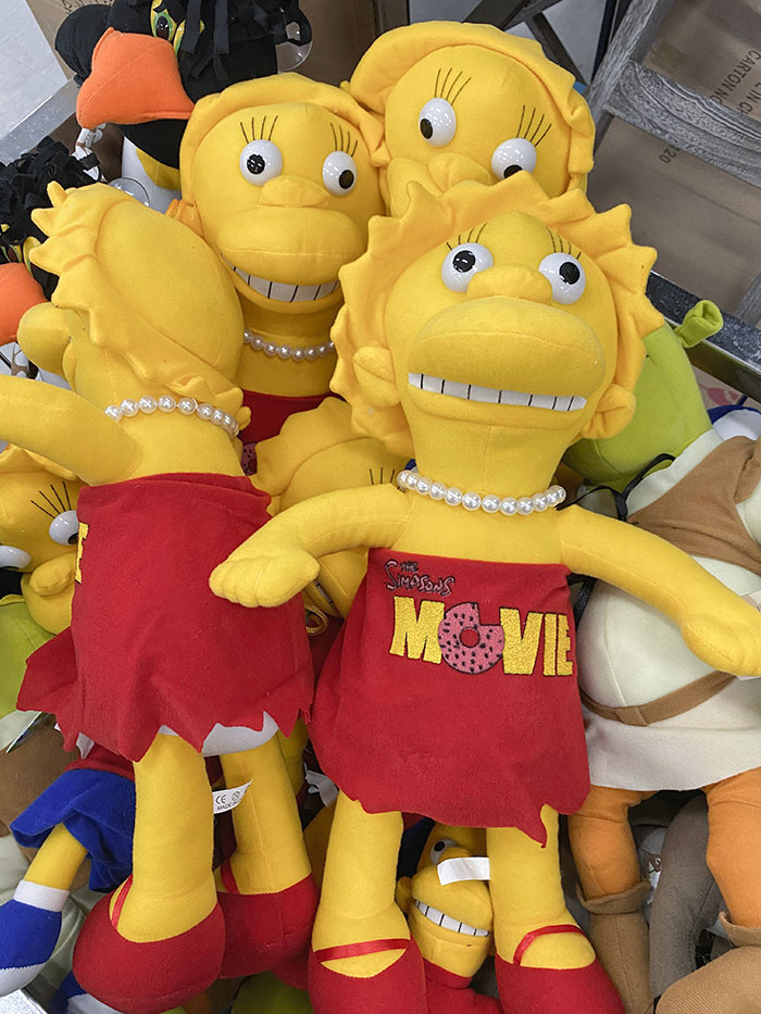 Yellow creepy toys resembling a cartoon character with wide eyes and unsettling smiles in a pile of various plush toys.