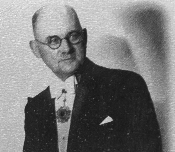 Black and white photo of a man in glasses and formal attire representing unexpected acts of kindness in history.