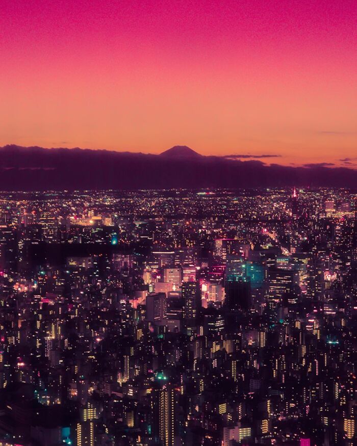 Tokyo cityscape at night with vibrant lights under a colorful sky, showcasing surreal urban beauty in Japan.