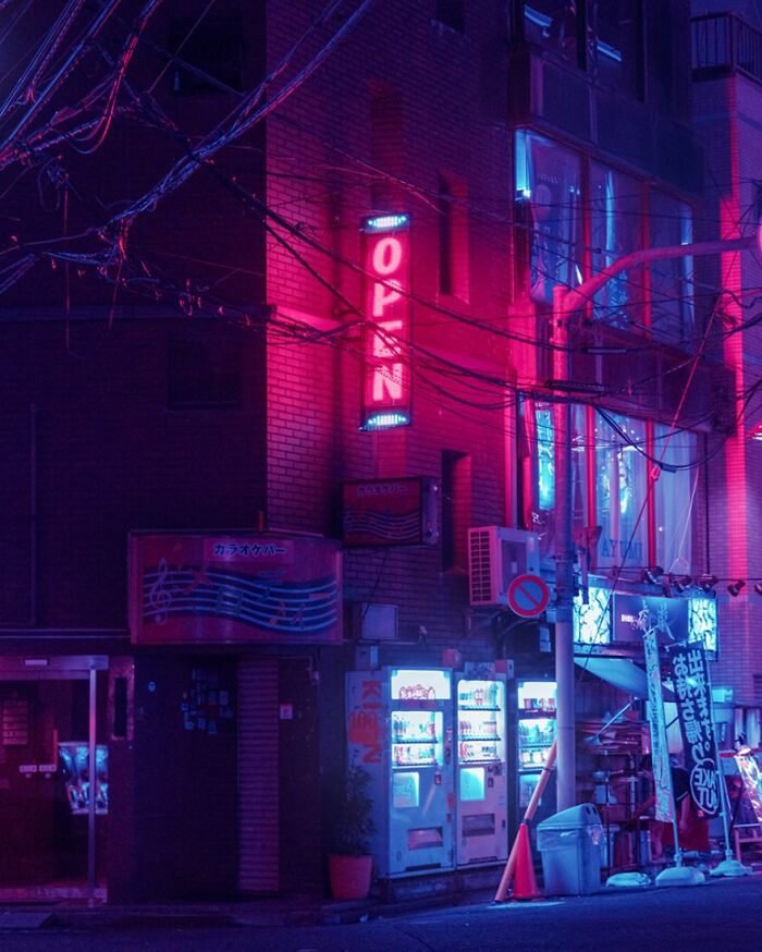 Neon-lit Tokyo street at night with vending machines and glowing open sign in surreal Japan cityscape.