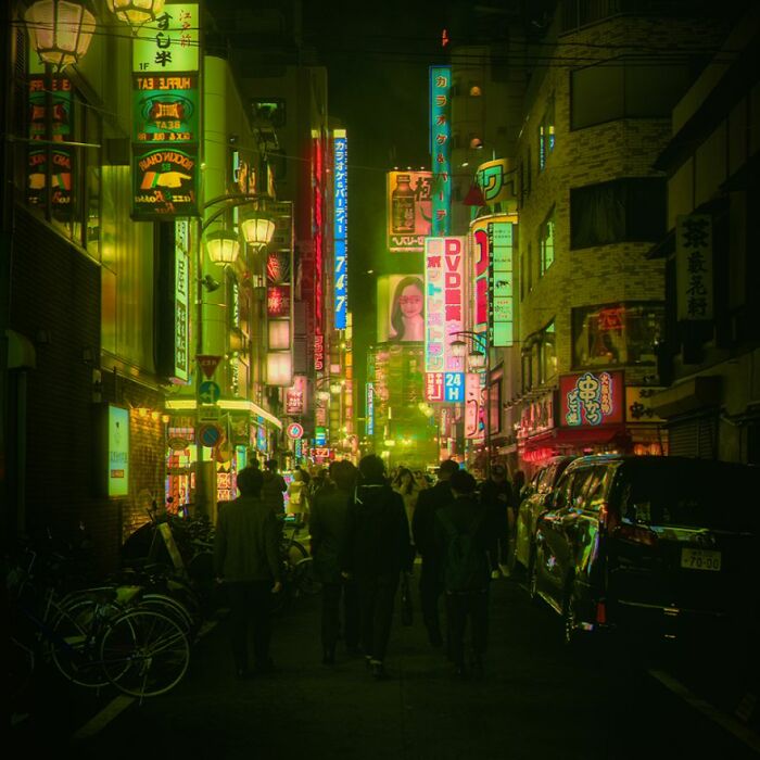 Crowded street in Tokyo at night illuminated by neon signs, capturing the surreal cityscape of Japan after dark.