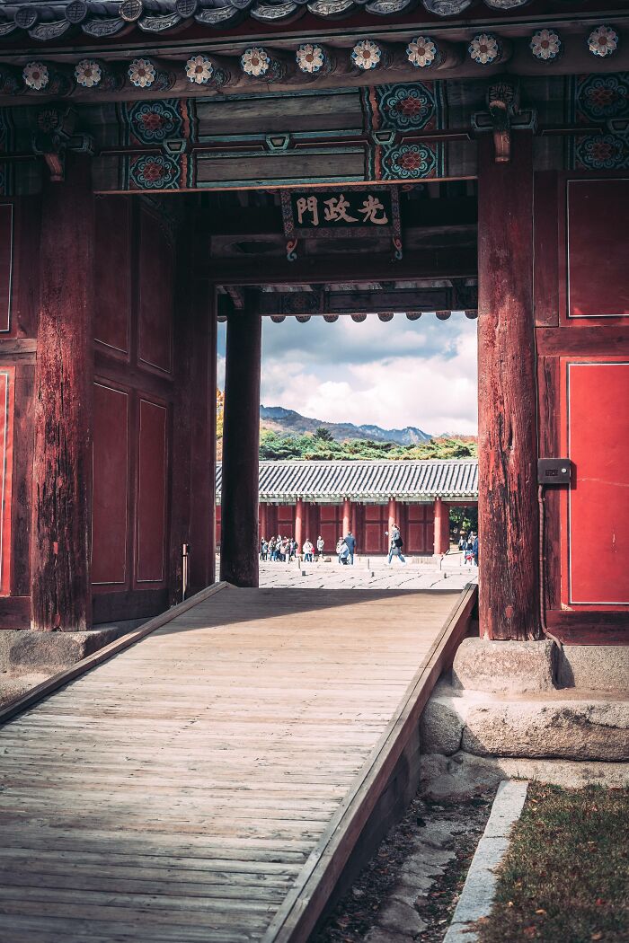 Traditional Korean palace gate and wooden pathway with visitors, showcasing the beauty of Seoul city architecture.