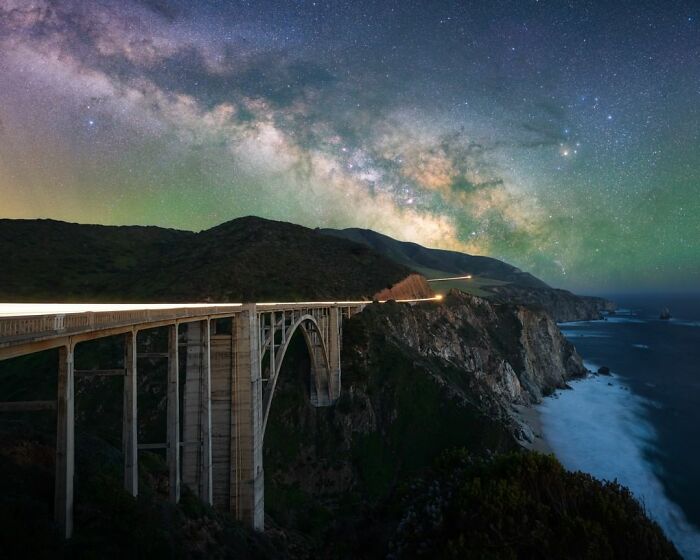 Nightscape view of a bridge under a starry sky along a dramatic coastline.