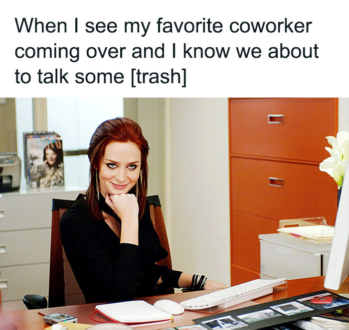 Person at office desk with a sly smile, amused by a funny office moment. Corporate humor captured in a meme.