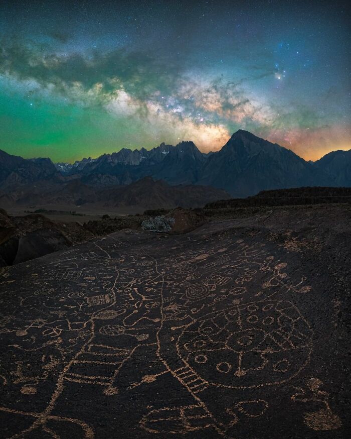 Nightscape featuring starry sky over mountains and ancient petroglyphs, showcasing the beauty of night photography.