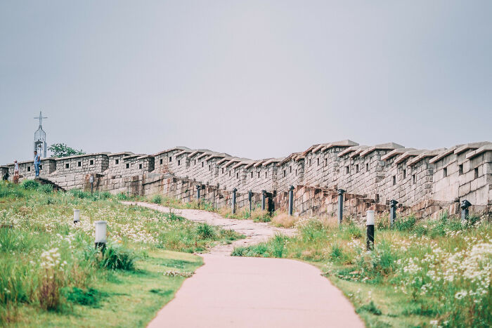 Stone wall and pathway surrounded by greenery in Seoul, showcasing the beauty of the cityscape and historic architecture.