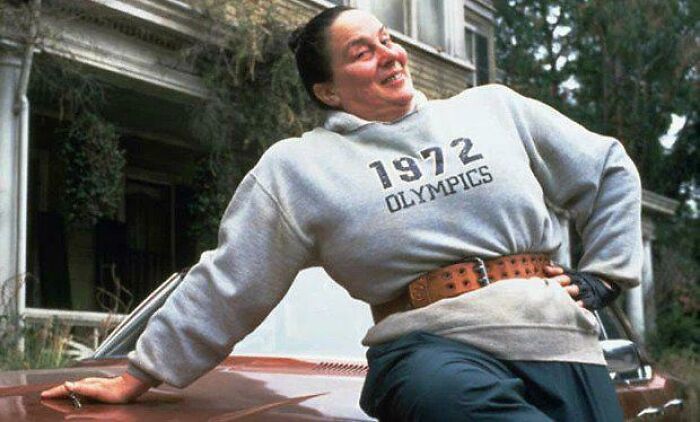 Woman in a 1972 Olympics sweatshirt leaning on a car, scene highlighting Easter eggs and hidden details from popular films.