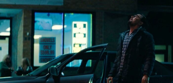 Man standing next to a car at night outside a store, referencing Easter eggs and hidden details from popular films.