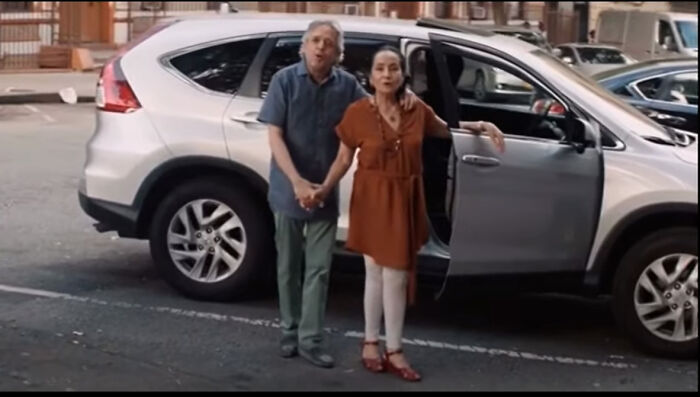 A man and woman standing beside an open car door in a parking lot, highlighting Easter eggs from popular films.