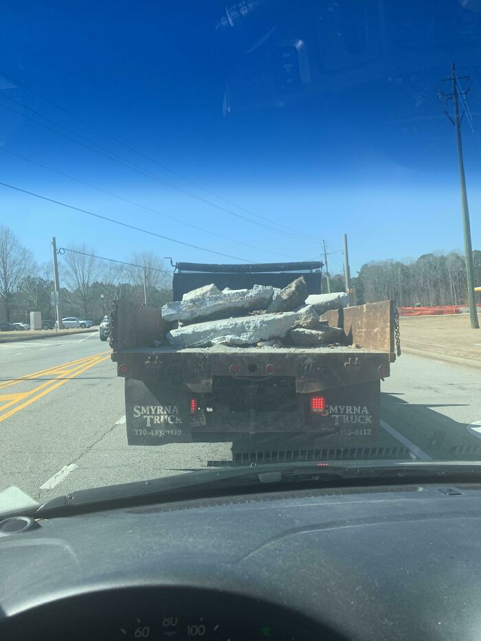 Conduciendo detrás de una camioneta comercial sin puerta que lleva escombros sueltos sin asegurar