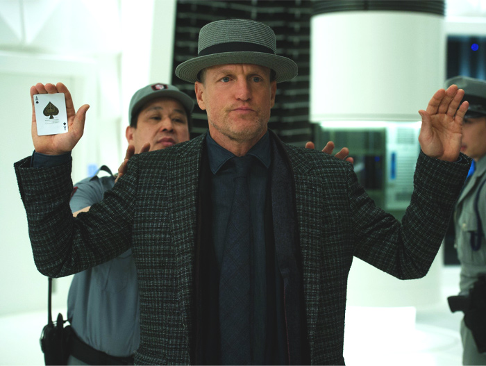 Woody Harrelson raising his hands, in one of which there is the card