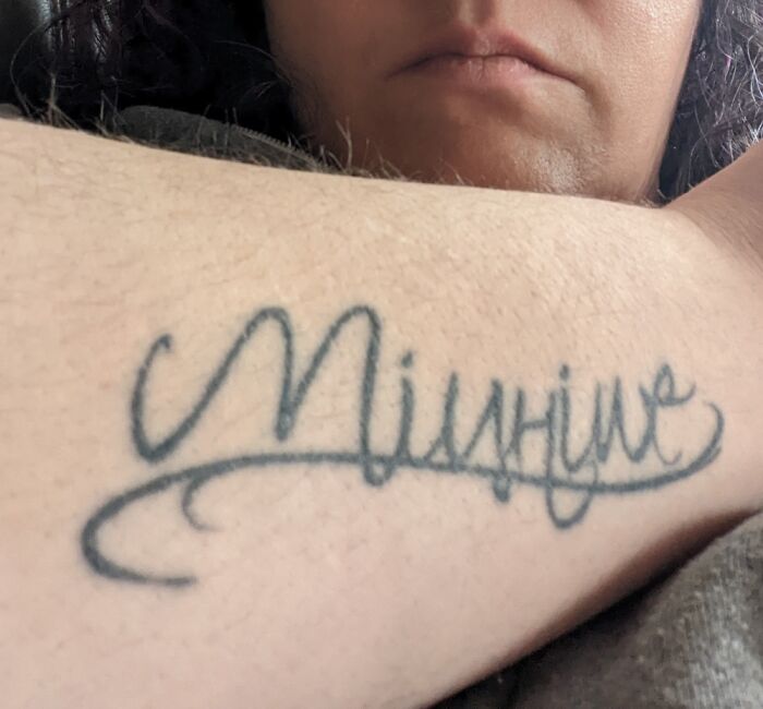 Close-up of a tattoo with cursive lettering on a person's forearm, showcasing body art.