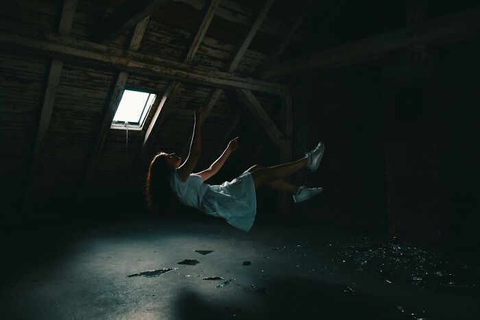 Person levitating in a dark attic, illustrating the feeling of passing away as described by those who came back to life.