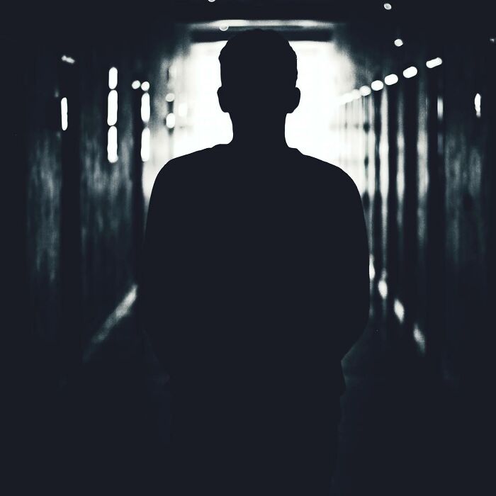 Silhouette of a person walking through a dark hallway with bright light ahead representing near-death experience themes.