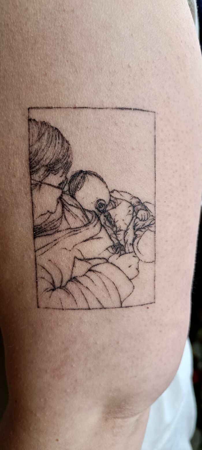 Tattoo of a person embracing a baby, detailed linework on skin.