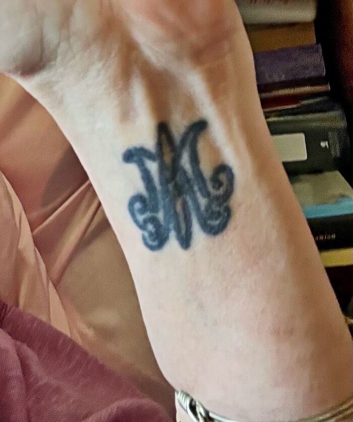 Tattoo of decorative initials on a person's wrist, showcasing unique body art.