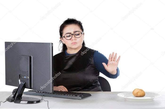 Woman in glasses ignoring a potato on a plate while using a computer, showcasing a weird stock image.