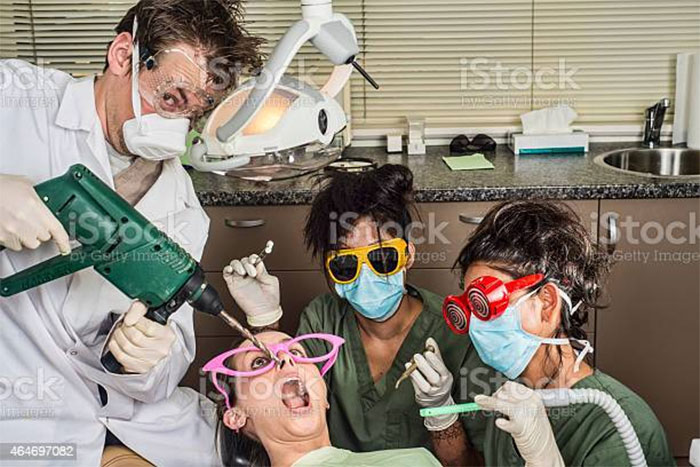 Dentist using a power drill on patient with colorful sunglasses, surrounded by quirky assistants, showcasing weird stock images.