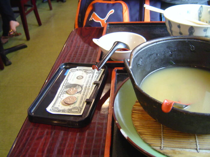 Money and coins placed on a tray beside a pot of soup, illustrating common big scams many people don't realize.
