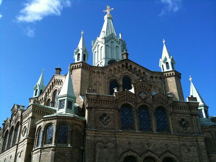 Historic church building with intricate architecture and spires against a clear blue sky, illustrating big scams concept.