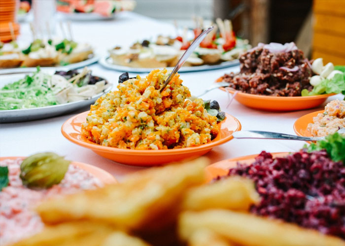 Colorful lentil salad and assorted appetizers served on orange plates at a buffet table for delusional conversations.