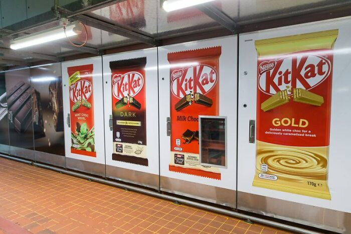 KitKat chocolate bar advertisements in a subway station highlighting popular candy brands linked to big scams discussions.