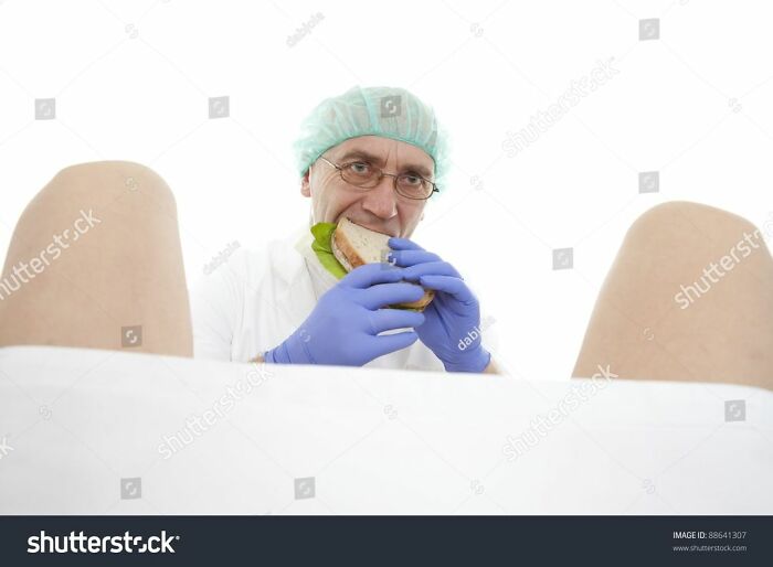 A doctor in scrubs eating a sandwich between a patient's legs in a weird stock image.